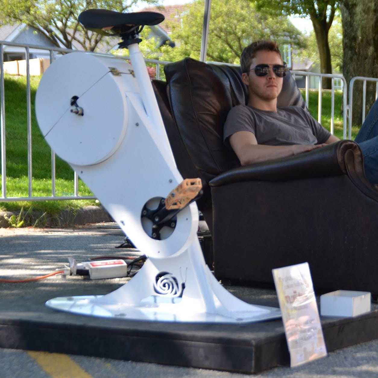 A single gSnails stool at an outdoor eatART event, a rider relaxing in a leather chair beside it